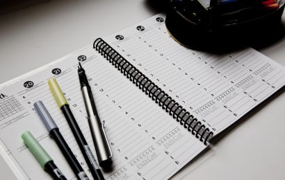 Open planner with pens on a desk, symbolizing realistic goal setting, habit building, and planning for the new year.