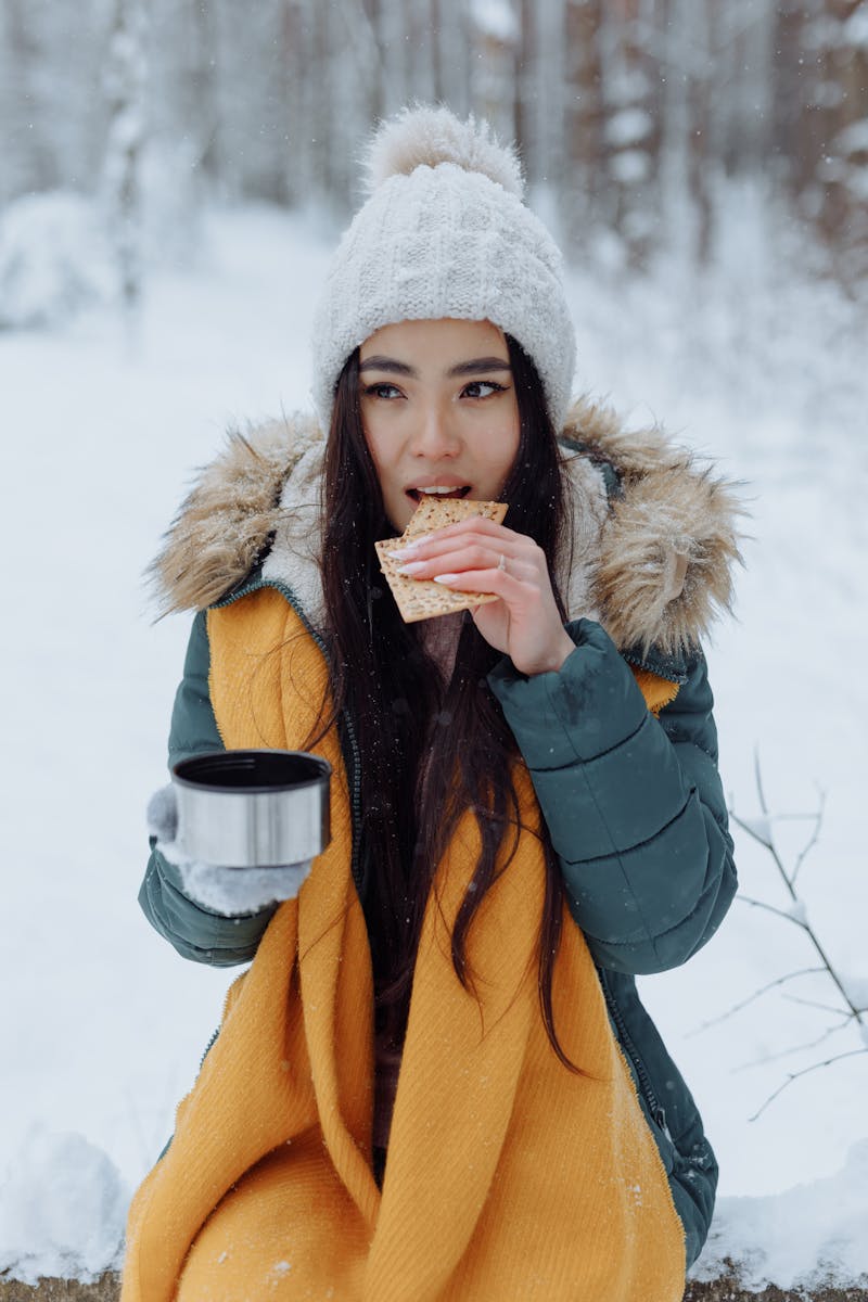 how can I stay healthy during winter trips - woman eating crackers outdoor snow