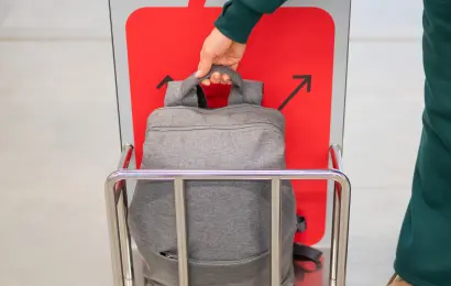 Carry-on backpack placed inside an airport baggage size sizer, illustrating airline cabin baggage rules and the risk of extra fees for oversized luggage.