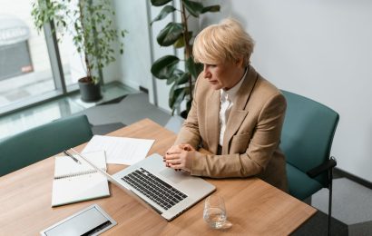 Businesswoman sitting at desk with laptop and notebook, reflecting on goals and planning next steps