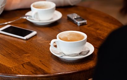 Two smartphones sitting on a cafe table during a coffee date, representing the most common places people lose their phone.