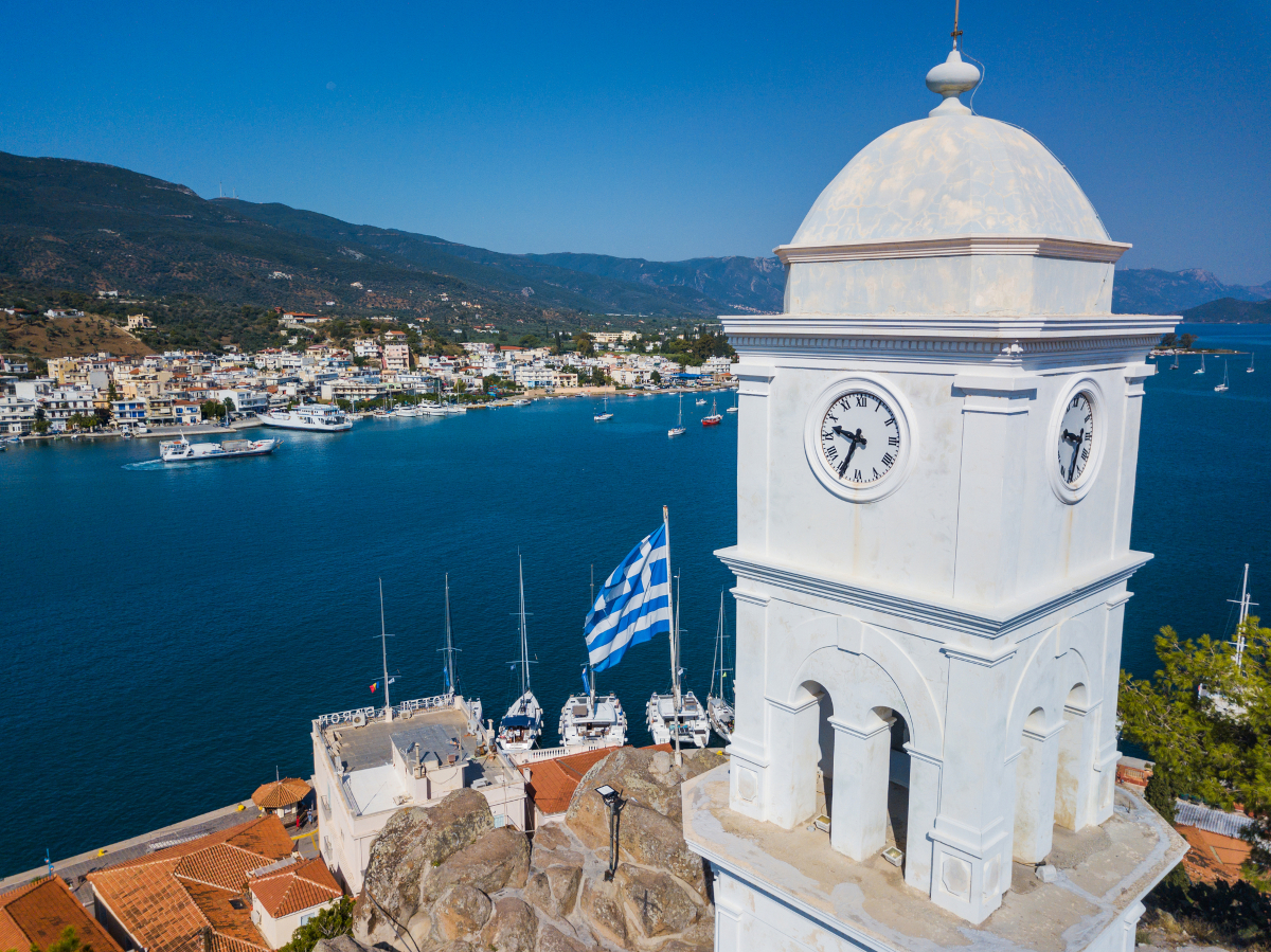 Clock tower on Poros Island in Greece overlooking the sea, representing Greek proverbs about luck, timing, and daily life