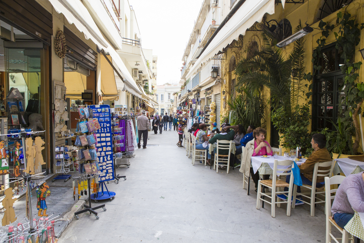 People sitting outside a traditional Greek tavern in Athens, representing Greek proverbs about speech, gossip, and reputation