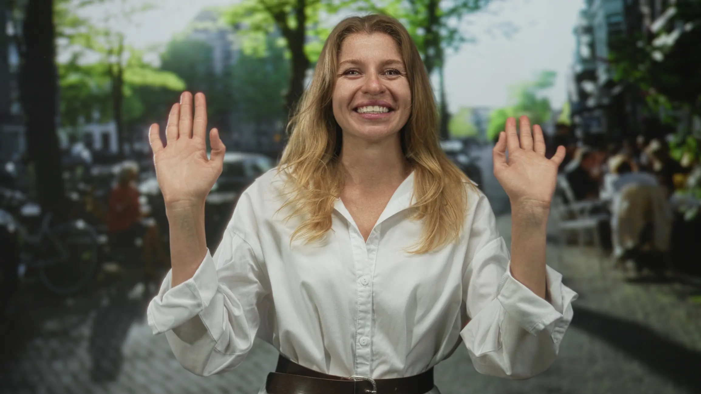 White woman smiling with both hands raised in a polite refusal gesture