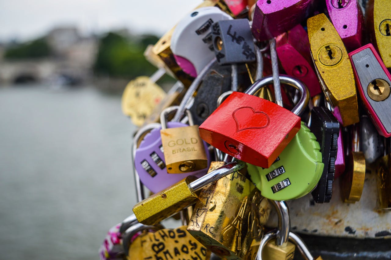 Close up of colorful love padlocks with a red heart lock attached to a bridge railing over the Seine River in Paris France.