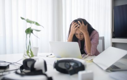 Stressed small business owner holding her head while working on a laptop, showing frustration with slow business growth