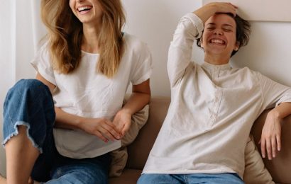 Two adults laughing together at home, showing how to have more fun as an adult without spending more money