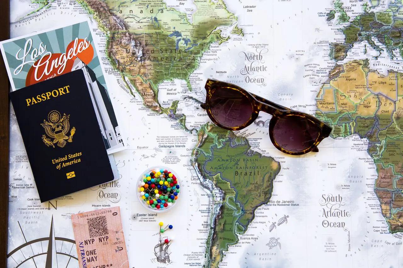 Passport, travel ticket, sunglasses, and world map used for checking documents before an international trip