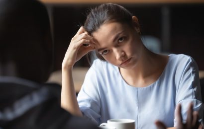 Woman looking uncomfortable during a cafe conversation, for an article about how to change the subject when a conversation gets awkward