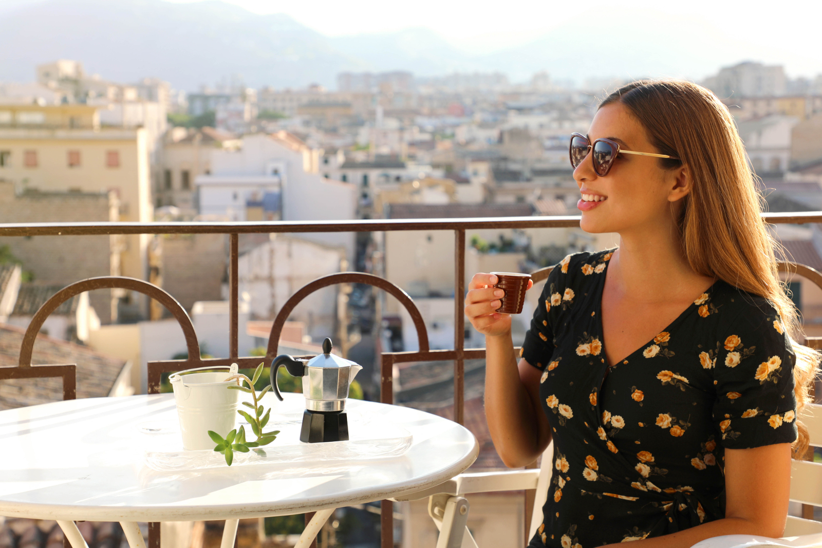 Woman drinking Italian coffee on a terrace with city views in Italy suggesting Italian dining rules