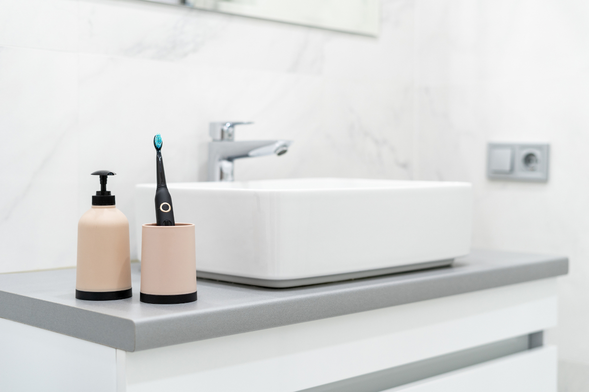 Electric toothbrush and toiletries on hotel bathroom counter before checkout