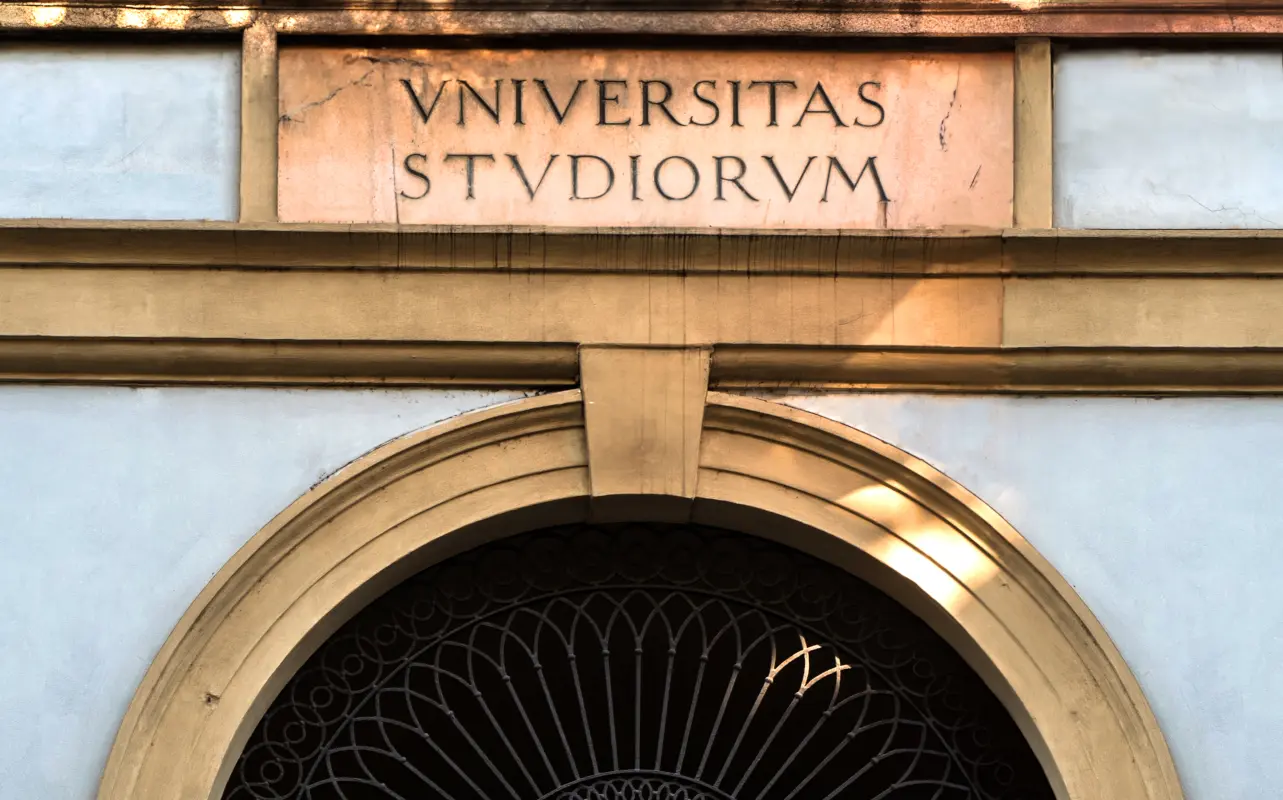 Latin inscription Universitas Studiorum above a university entrance