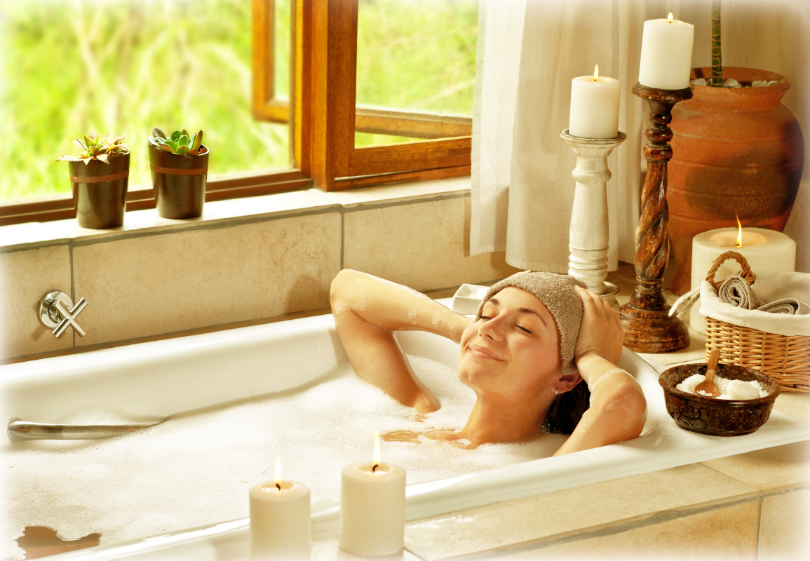 Woman relaxing in a candlelit bath for a home spa staycation