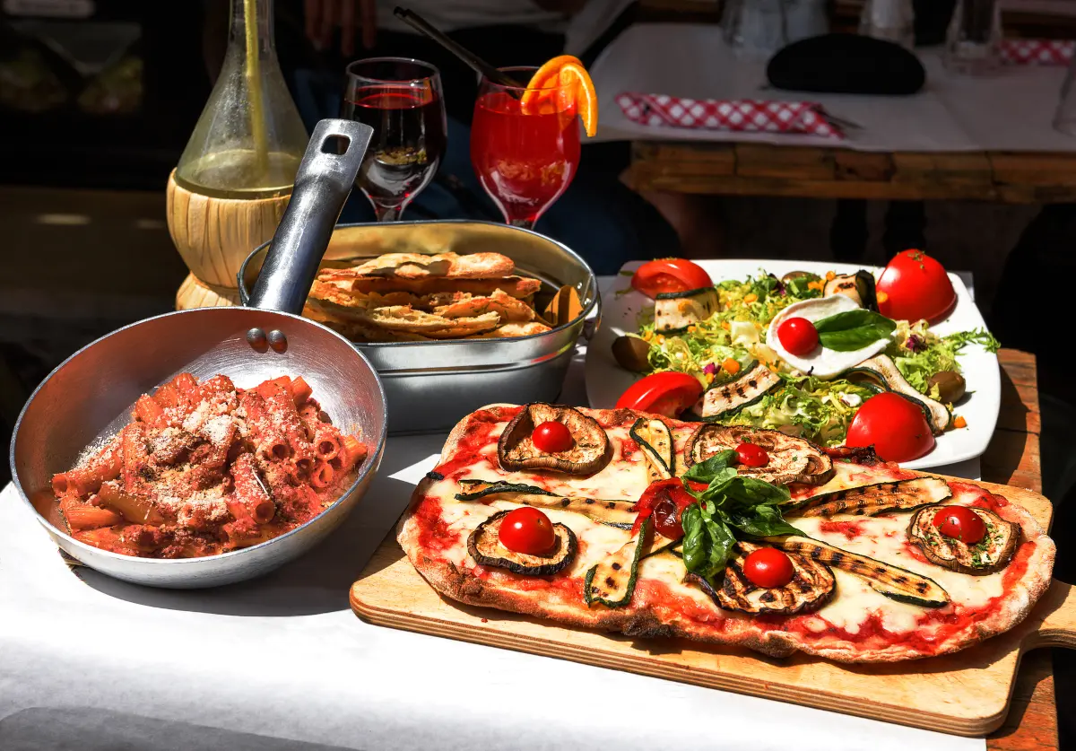 Italian restaurant table with pasta, pizza, salad, wine, and aperitivo drinks - Italian menu explained