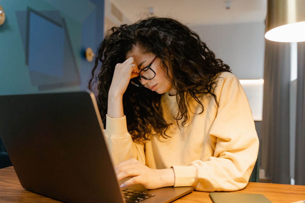 Tired woman working on laptop after taking on too many small favors. How to say no to a favor without being rude