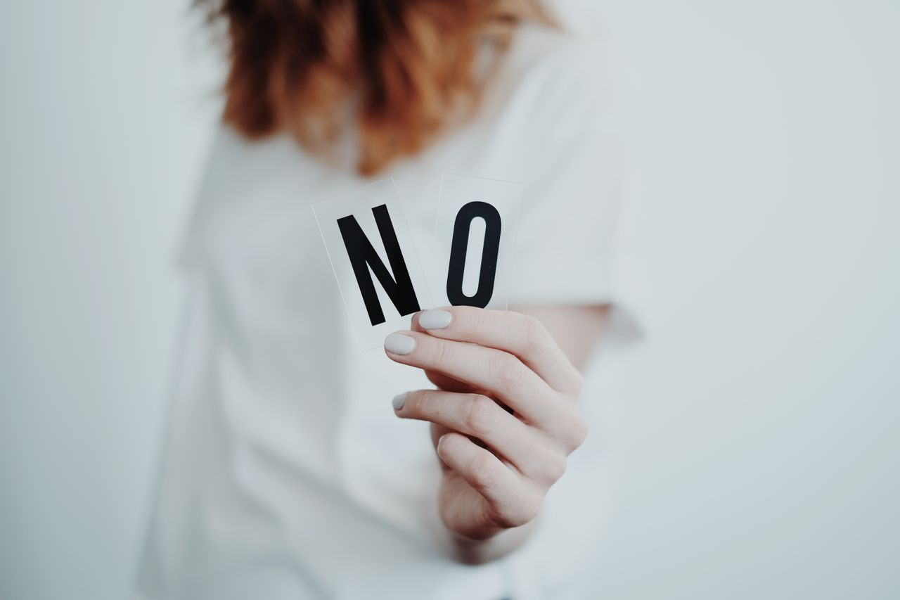 Woman holding a no sign as a symbol of setting boundaries with unsolicited advice