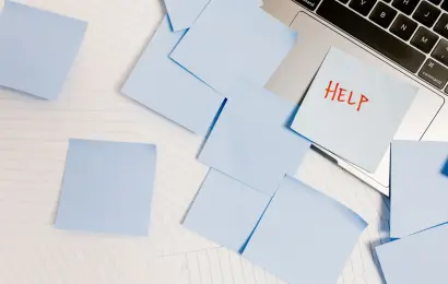 Sticky notes around a laptop with the word help for an overwhelming to-do list
