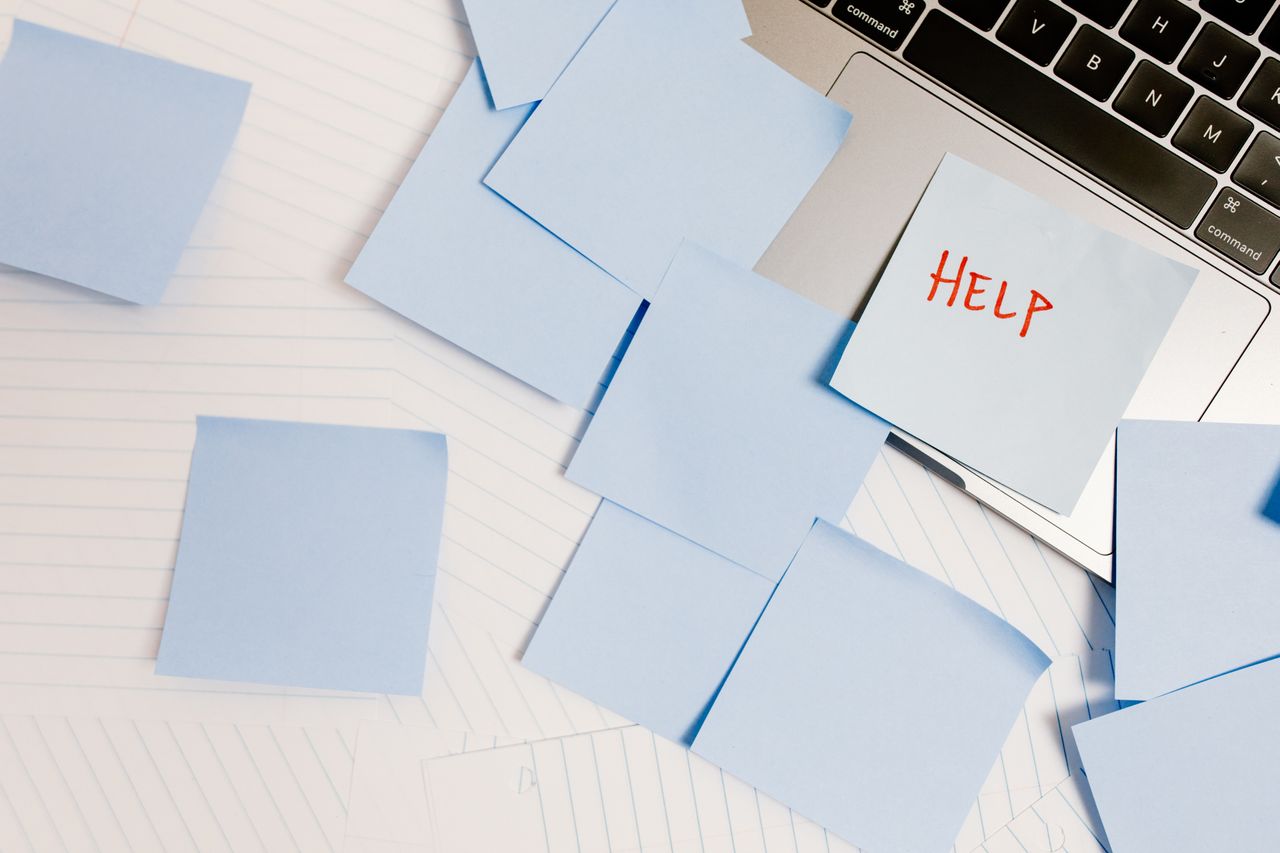 Sticky notes around a laptop with the word help for an overwhelming to-do list