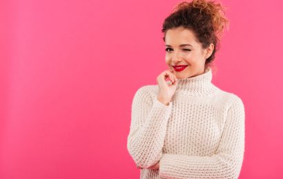 Smiling woman winking against a pink background