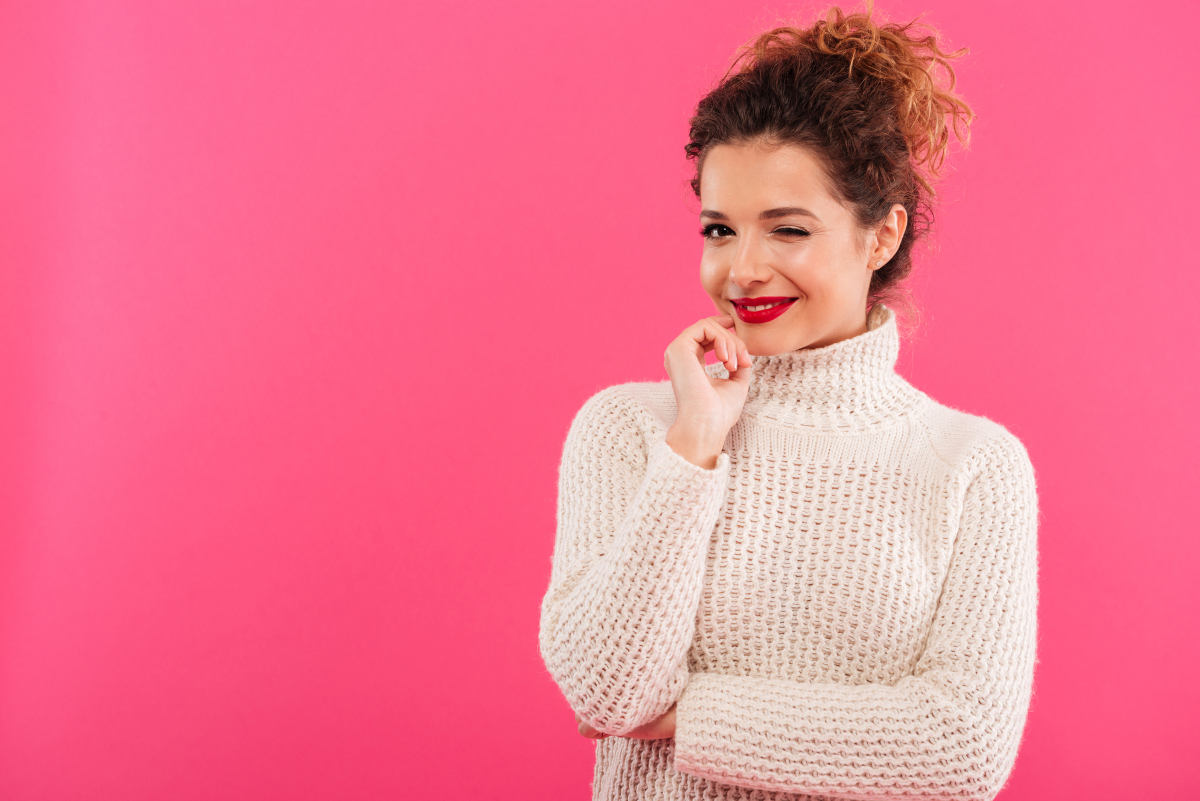 Smiling woman winking against a pink background
