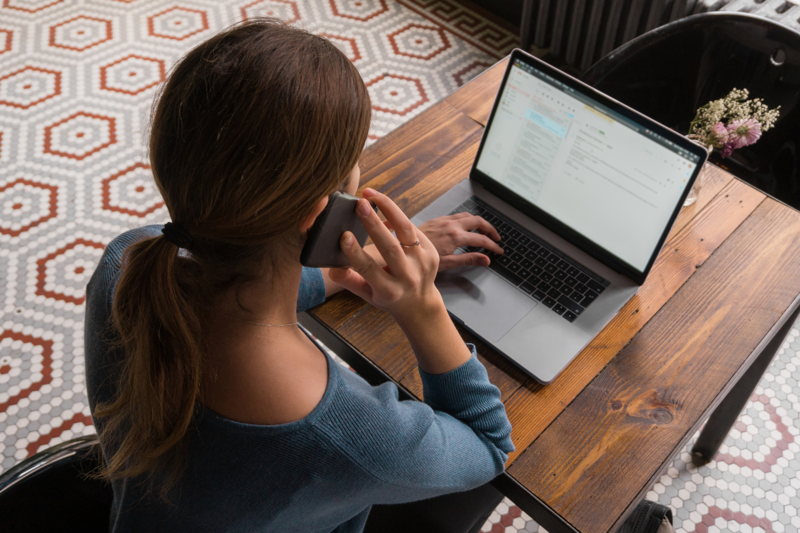 Professional woman writing a business email while speaking on the phone