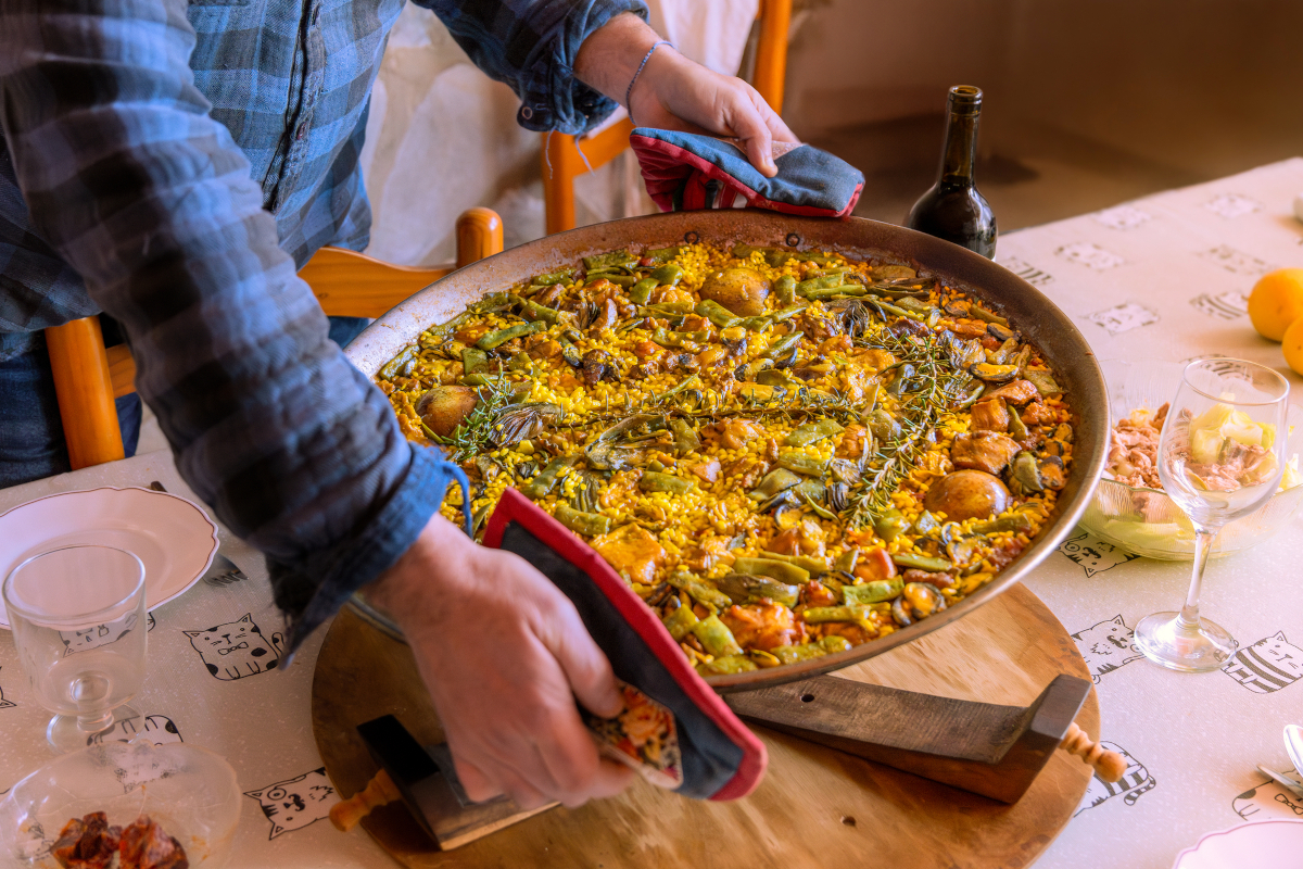 Traditional Valencian paella served on a wooden placemat on a rustic table for surprising Spain facts