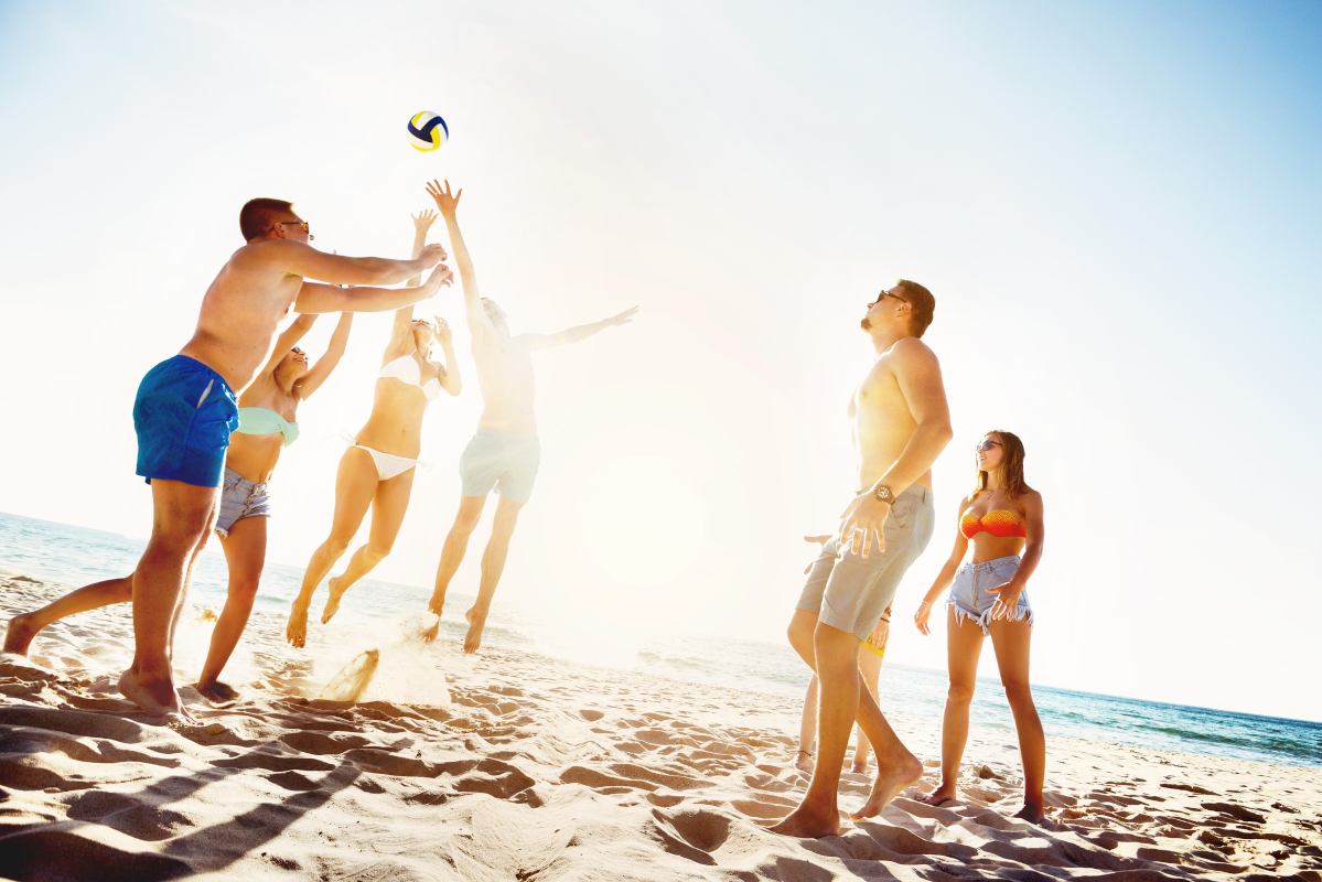 Friends playing volleyball on the beach for a summer quiz article