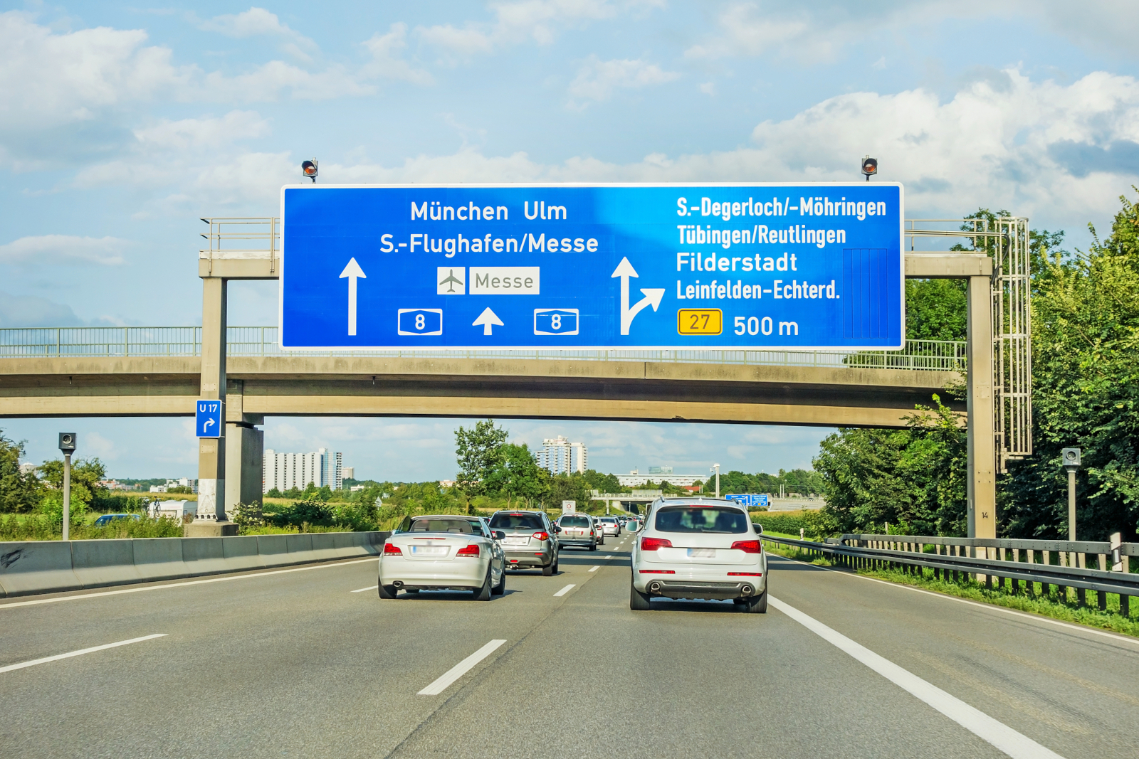 Cars driving on the German Autobahn beneath road signs for Munich and Ulm