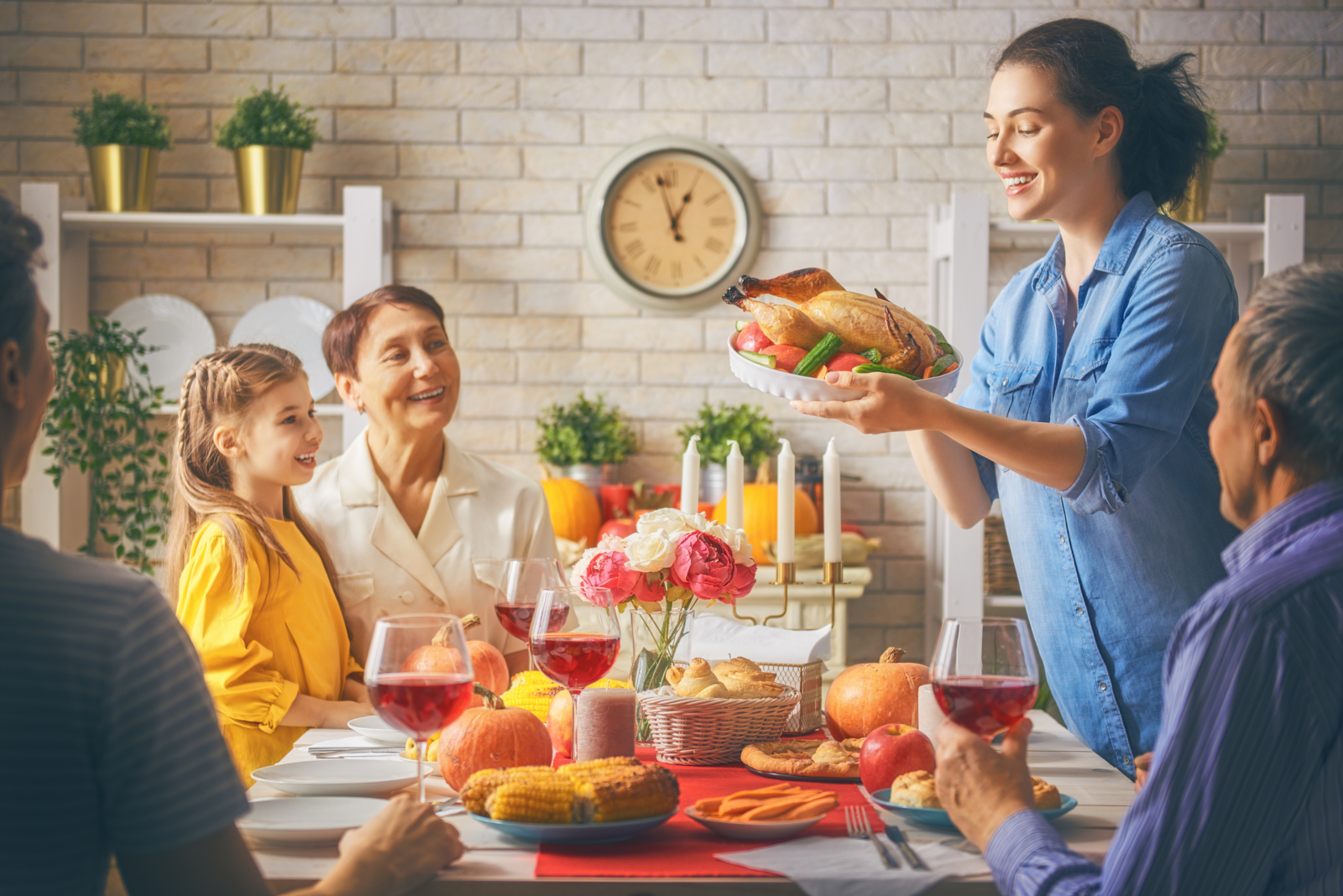 Family gathered around a roast turkey for Thanksgiving dinner for an article with 200 Thanksgiving Trivia Questions and Answers - Easy to Hard