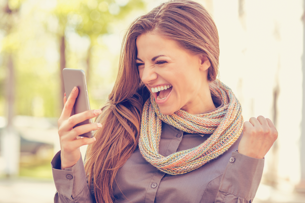 Young woman reacting happily to good news on her phone