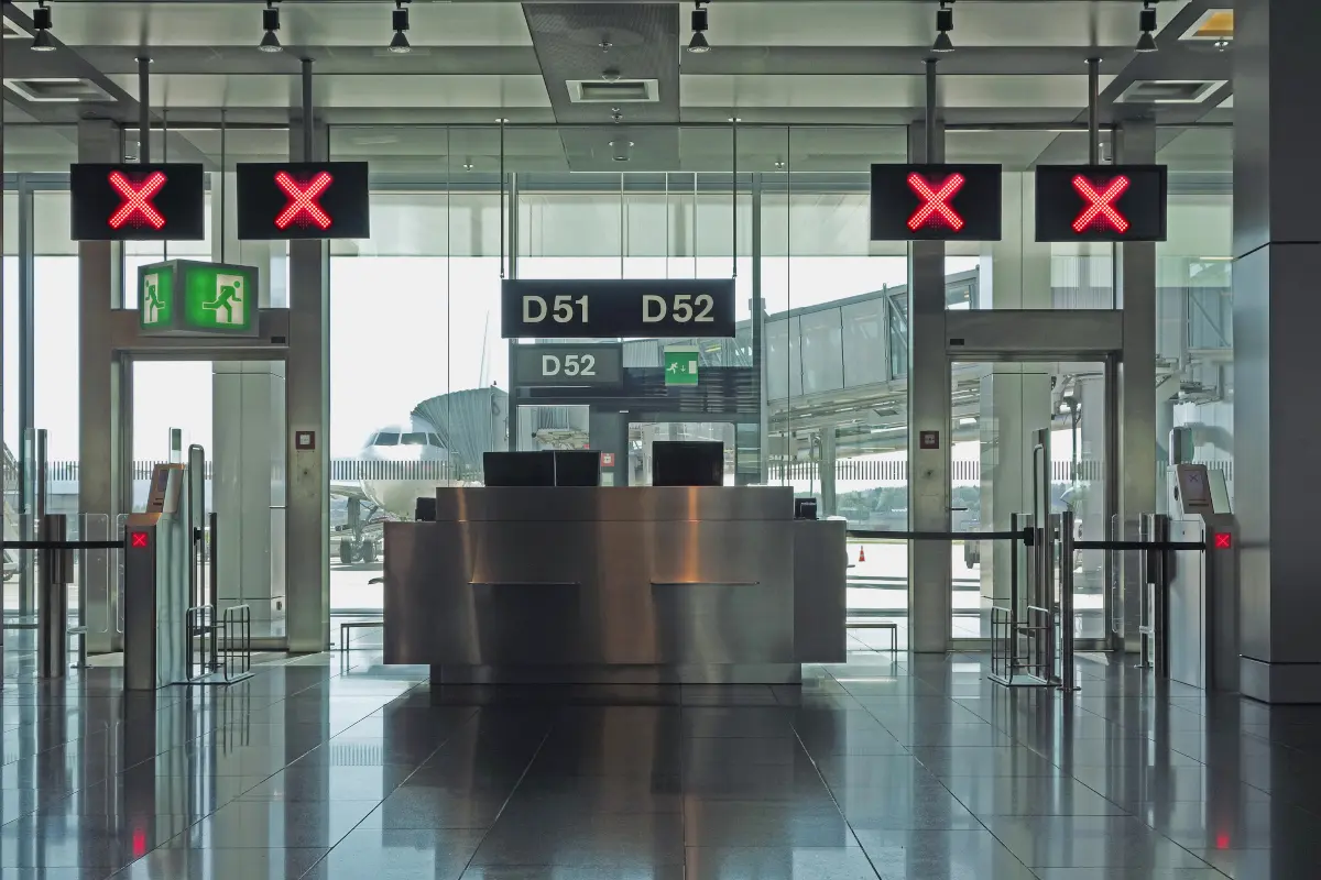 Closed airport departure gates with red signs and an airplane outside