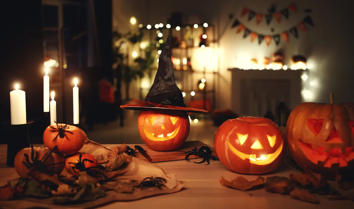 Carved jack-o'-lantern pumpkins in a dark Halloween-decorated room