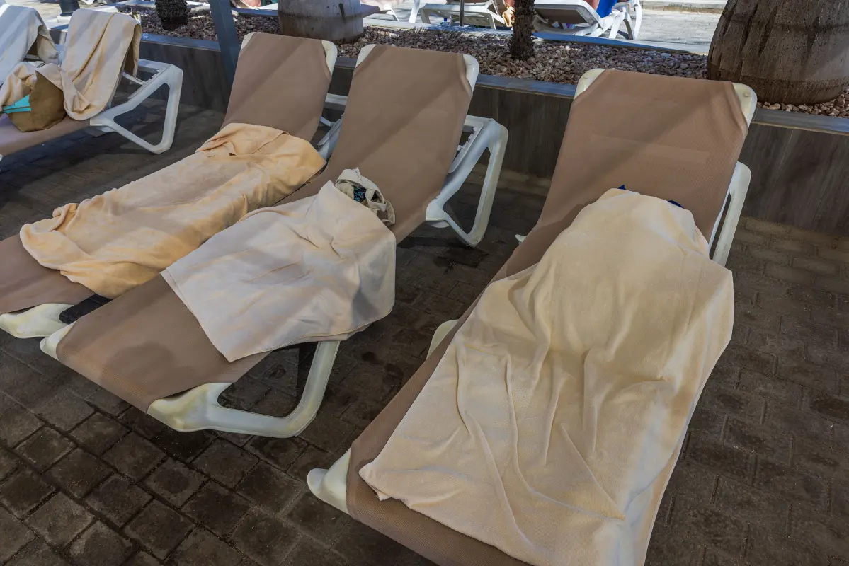 Sun loungers with towels beside an outdoor hotel swimming pool