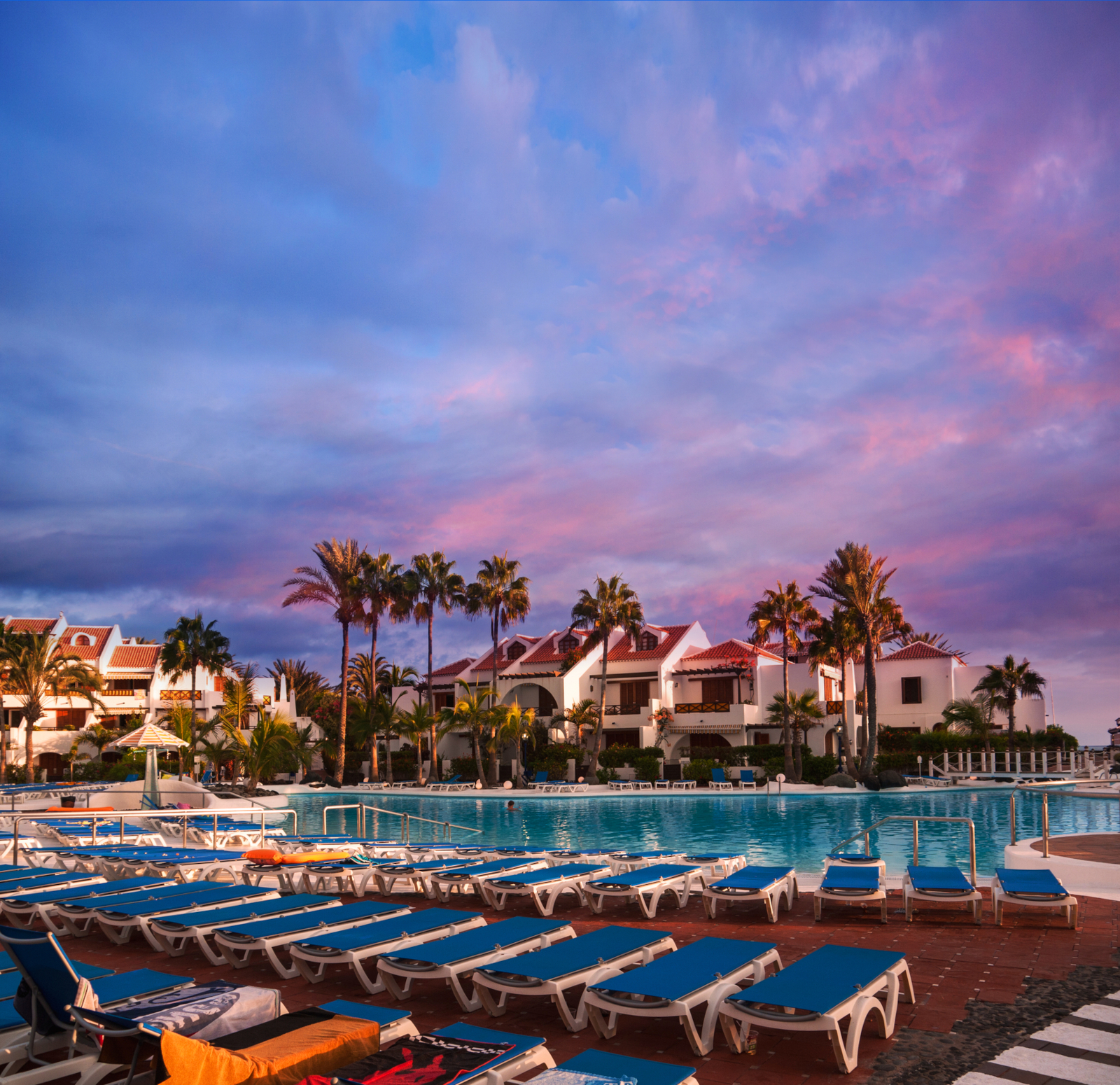 Hotel swimming pool with sunbeds at sunset in Tenerife, Spain