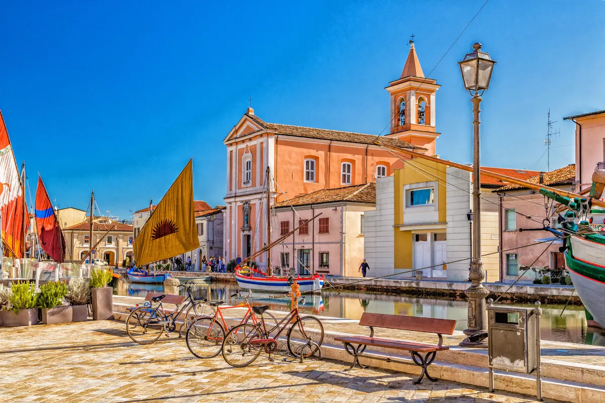 Church, bycicles and ancient boats on Canal Port in Cesenatico, Italy