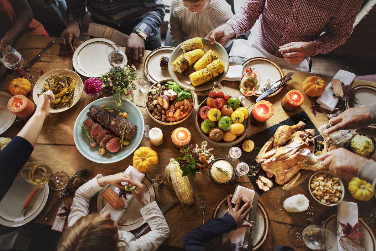 People serving turkey, corn and side dishes at a Thanksgiving dinner