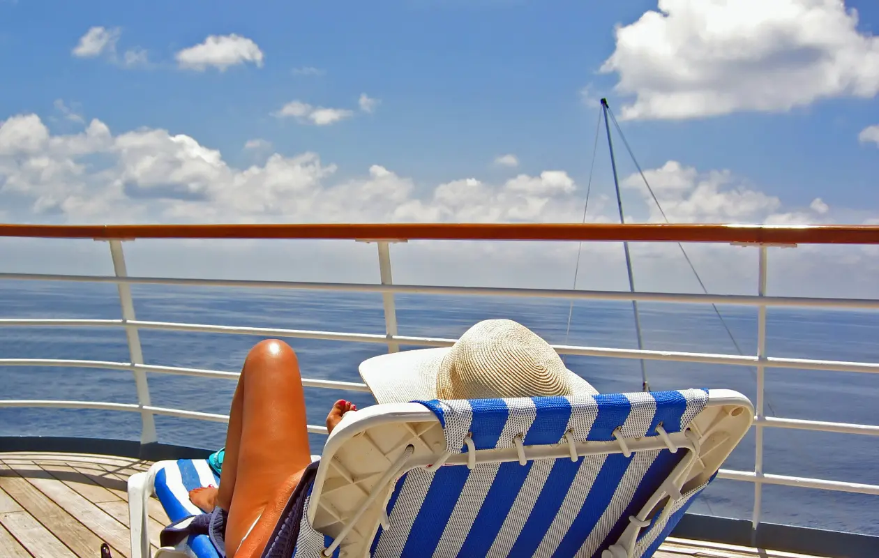 View from the Cruise Deck. A woman sits on the upper deck of a cruise ship and overlooks the ocean