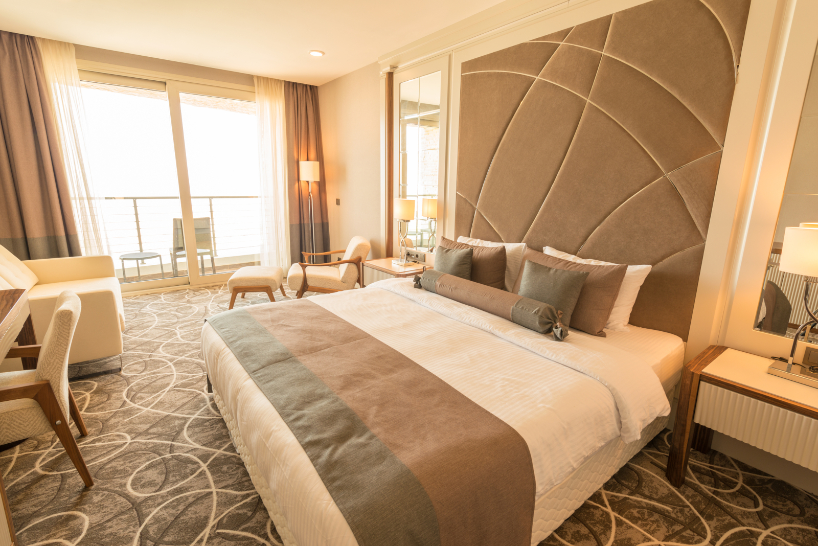 Modern hotel room interior with a large bed and seating area