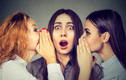Three young women telling whispering a secret gossip