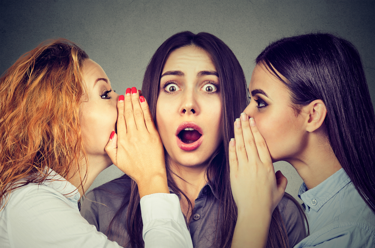 Three young women telling whispering a secret gossip
