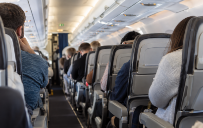 Passengers seated inside a commercial airplane cabin, viewed from behind