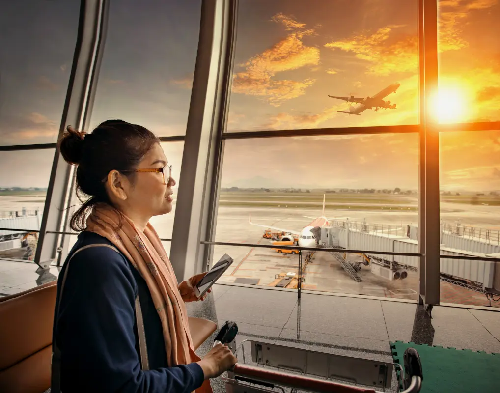 Woman checking her smartphone at an airport terminal with a passenger airplane outside