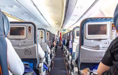 Passengers seated in an airplane cabin with seatback entertainment screens
