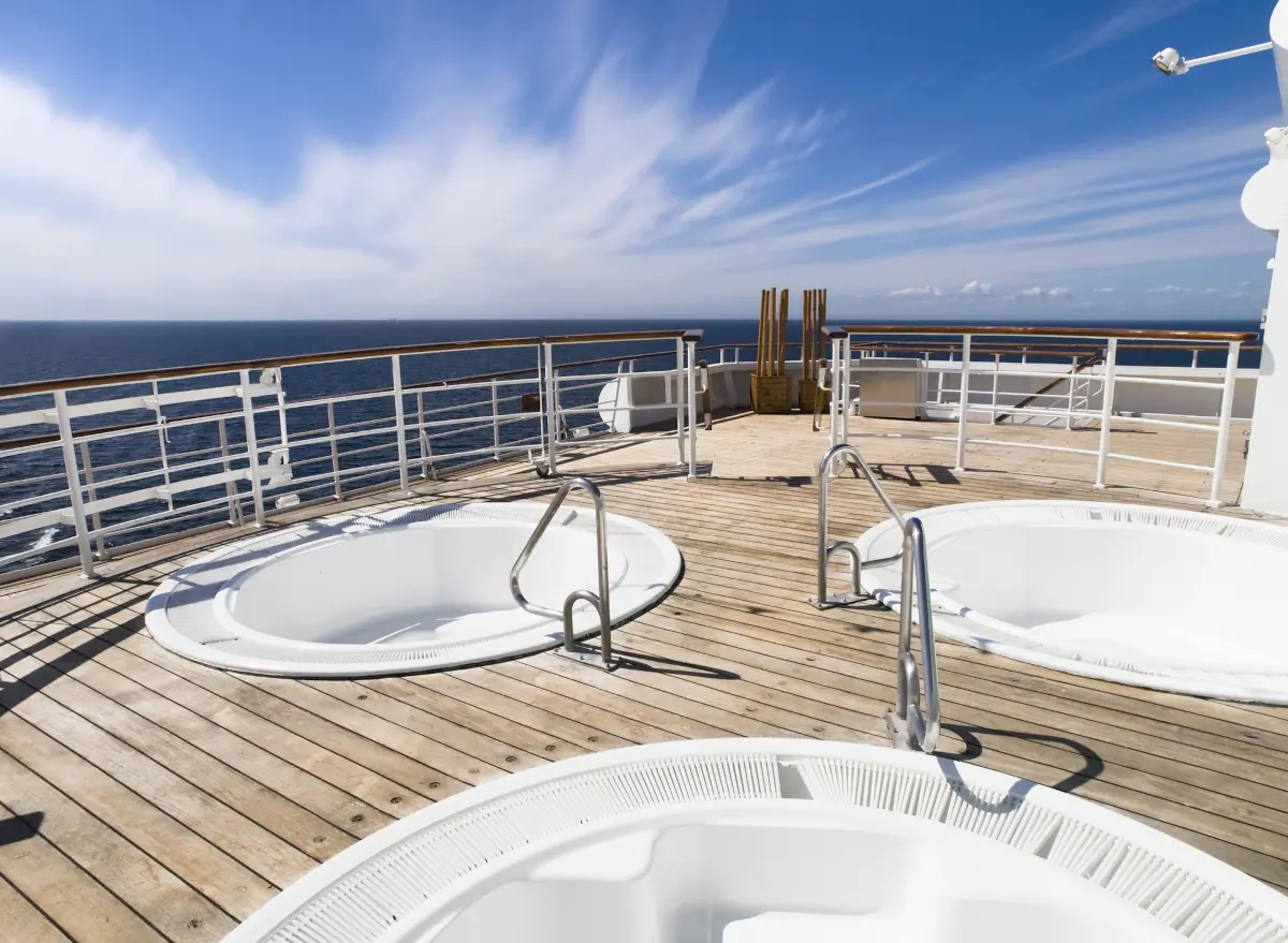 Three outdoor hot tubs on the sunny deck of a cruise ship