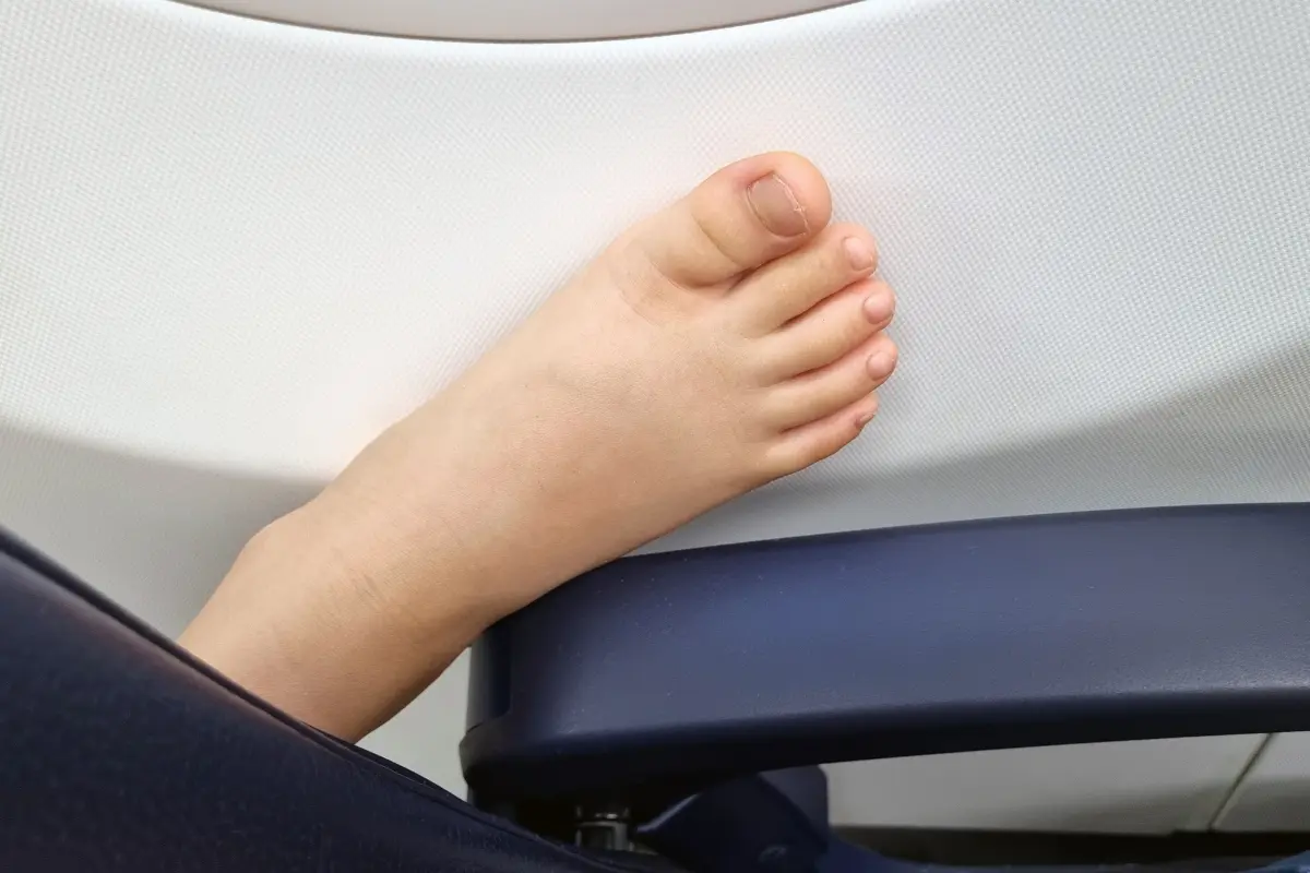 Child's foot resting on an airplane seat armrest during a flight